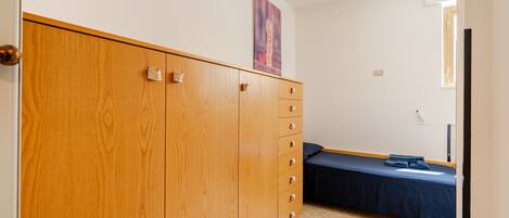 Un dormitorio con un armario de madera, una cama con cubrecama azul y un cartel colgado en la pared.