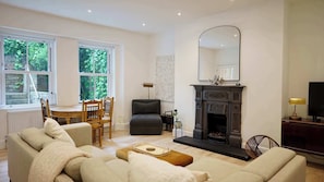A living room with a fireplace, a dining area with a table and chairs, and a sofa. - Spacious 1BDR Garden Flat in Charlton (London)