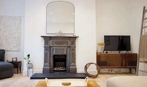 A living room with a fireplace, a television, and a sofa. - Spacious 1BDR Garden Flat in Charlton (London)