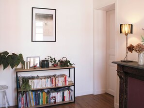 Ein Zimmer mit einem Bücherregal, einem gerahmten Bild, einer Lampe und einer Tür.