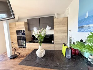 Een moderne keuken met een houten kast, een ingebouwde oven en een decoratieve vaas met bloemen.