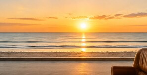 A beach view with a sunset, a chair, and a concrete ledge. - Sea & Pines Apt with Terrace (La Baule-Escoublac)