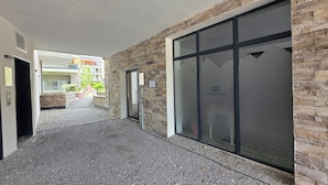 A hallway with stone walls, a glass door, and a sign indicating a legal office. - Bright, new apartment with a terrace 3* (Briançon)