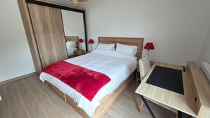 A bedroom with a bed, a mirror, two bedside tables with lamps, and a desk with a chair. - Bright, new apartment with a terrace 3* (Briançon)