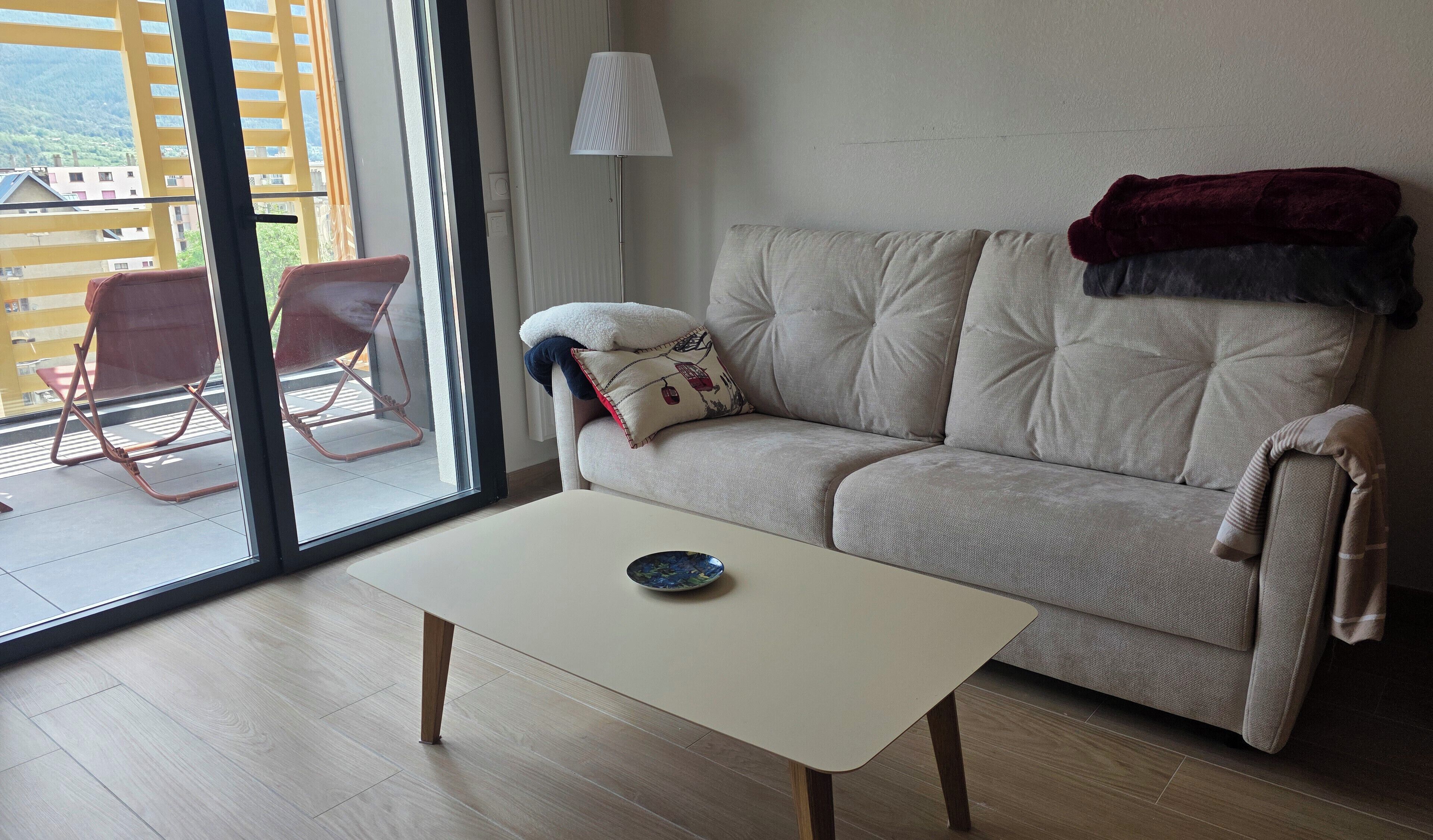 En stue med sofa, bord, lampe og udsigt ud