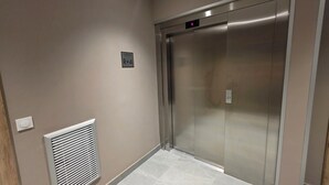 An elevator with a digital display showing the number 4, a sign above it reading 'NIVEAU R+4', and a vent on the wall to the left. - Bright, new apartment with a terrace 3* (Briançon)