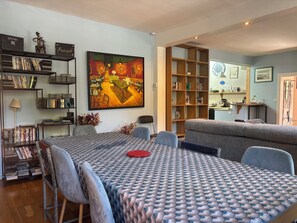 A living room with a dining table, chairs, a bookshelf, and a painting. - House with garden near Honfleur (Gonneville-sur-Honfleur)