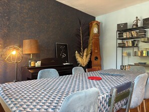 A room with a patterned tablecloth, a clock, a bookshelf, and a lamp. - House with garden near Honfleur (Gonneville-sur-Honfleur)