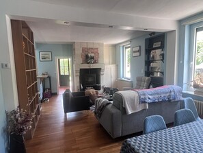 Ein geräumiger Wohnbereich mit Kamin, einer Couch, einem Esstisch und einem Bücherregal.