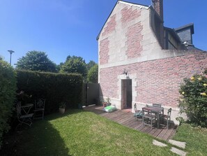 Ein Backsteinhaus mit einer Holzdielenveranda, einer Tür und einem kleinen Tisch mit Stühlen.