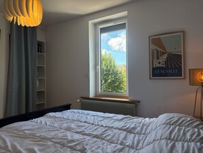 A bedroom with a bed, a window, a radiator, a shelf, and a framed picture on the wall. - House with garden near Honfleur (Gonneville-sur-Honfleur)