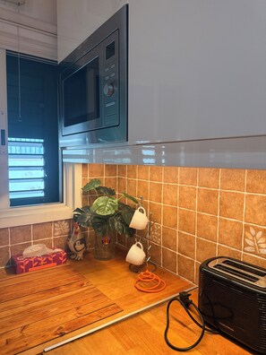 Eine Küche mit Mikrowelle, Toaster, einem Fenster und einem Blumentopf.