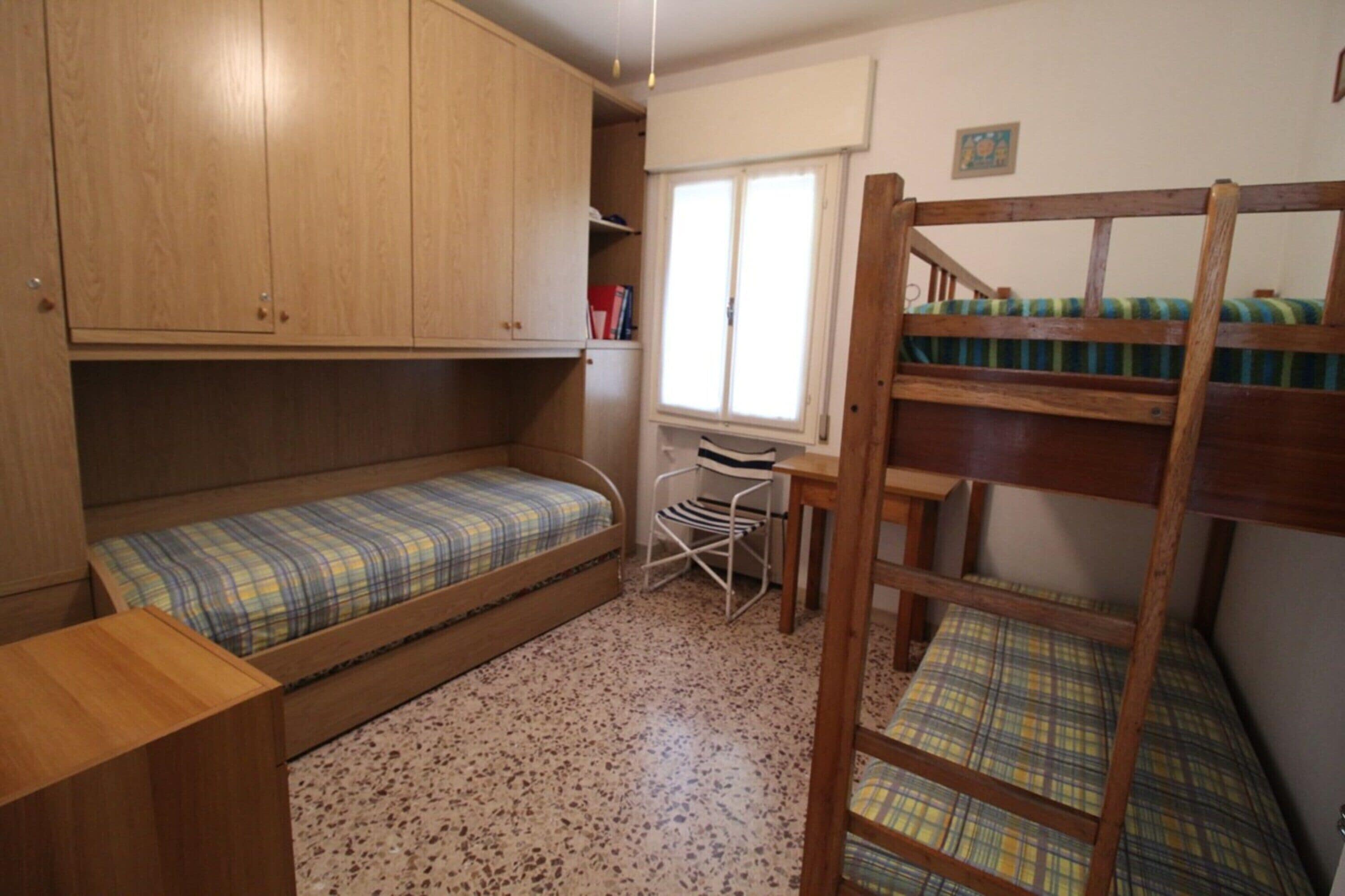Habitación pequeña con literas, un escritorio y una silla.