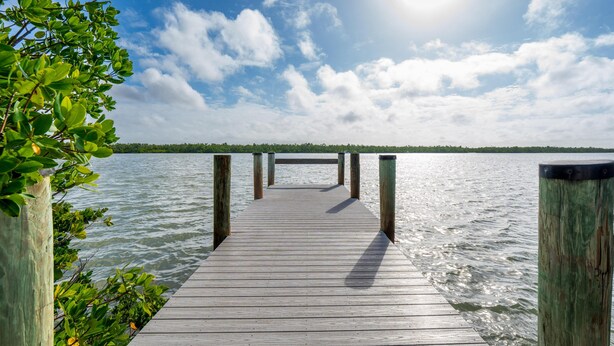 A wooden pier extending into calm water with a clear sky above. - Blue Bayou B (Fort Myers Beach)