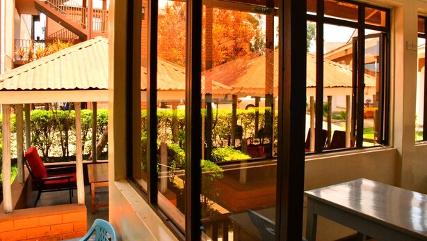A room with large windows, a table, and a chair. - Hotel Tausi (Rodi Kopany)