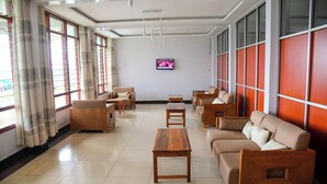 A spacious room with a sofa set, wooden tables, and a TV on the wall. - Hotel Tausi (Rodi Kopany)