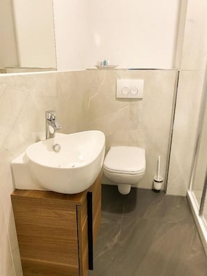 Une salle de bain avec un lavabo blanc, des toilettes et un sèche-mains.