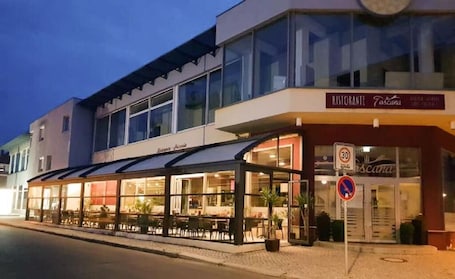 A restaurant with outdoor seating, a covered patio, and a sign indicating a 30 km/h speed limit.. Hotel Toscana