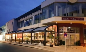 Ein Restaurant mit Außenbereich, einer überdachten Terrasse und einem Schild, das eine Geschwindigkeitsbegrenzung von 30 km/h anzeigt.