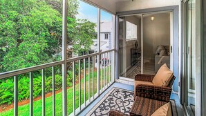 A balcony with wicker chairs, a patterned rug, and a view of greenery. - Luxury beach 2-bedroom condo in highly sought Cape Canaveral community  (Cape Canaveral)