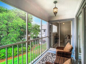 A balcony with wicker chairs, a patterned rug, and a view of greenery. - Luxury beach 2-bedroom condo in highly sought Cape Canaveral community  (Cape Canaveral)