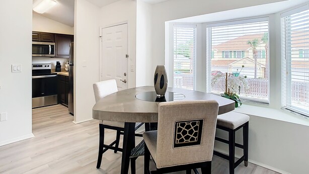 A modern kitchen with stainless steel appliances, a dining area with a round table and chairs, and a window with blinds. - Luxury beach 2-bedroom condo in highly sought Cape Canaveral community  (Cape Canaveral)