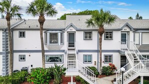 A two-story residential building with a white exterior, multiple windows, and a central staircase. - Luxury beach 2-bedroom condo in highly sought Cape Canaveral community  (Cape Canaveral)