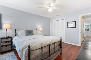 Ein Schlafzimmer mit einem Bett, Nachttischlampen, einem Deckenventilator, einem Kleiderschrank und einem gerahmten Bild an der Wand.