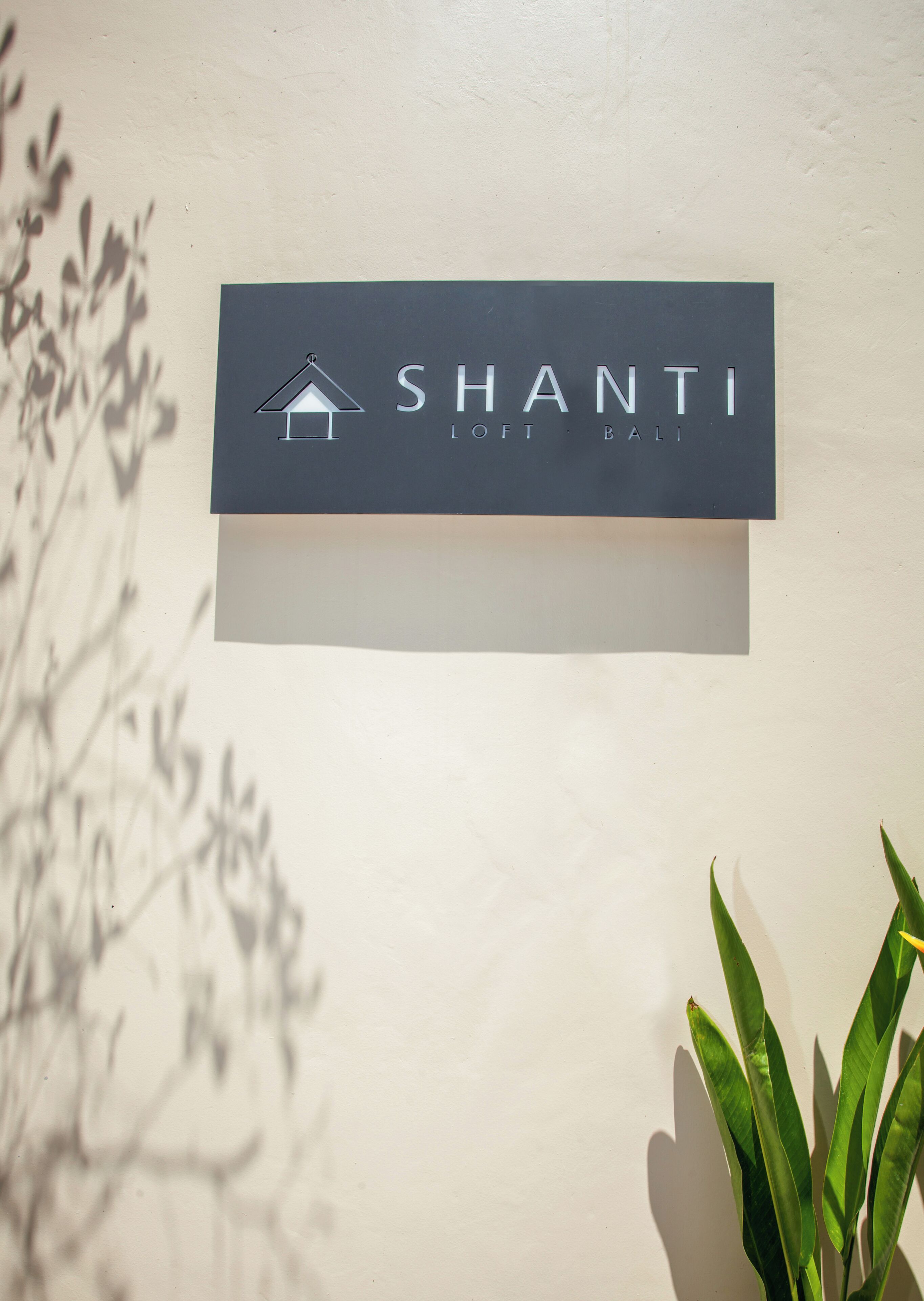 Ein Schild mit dem Namen 'SHANTI' und den Wörtern 'LOFT' und 'BALI' an einer Wand.