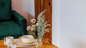 Una mesa redonda de madera con platos y tazas blancas, rodeada de sillas de madera.