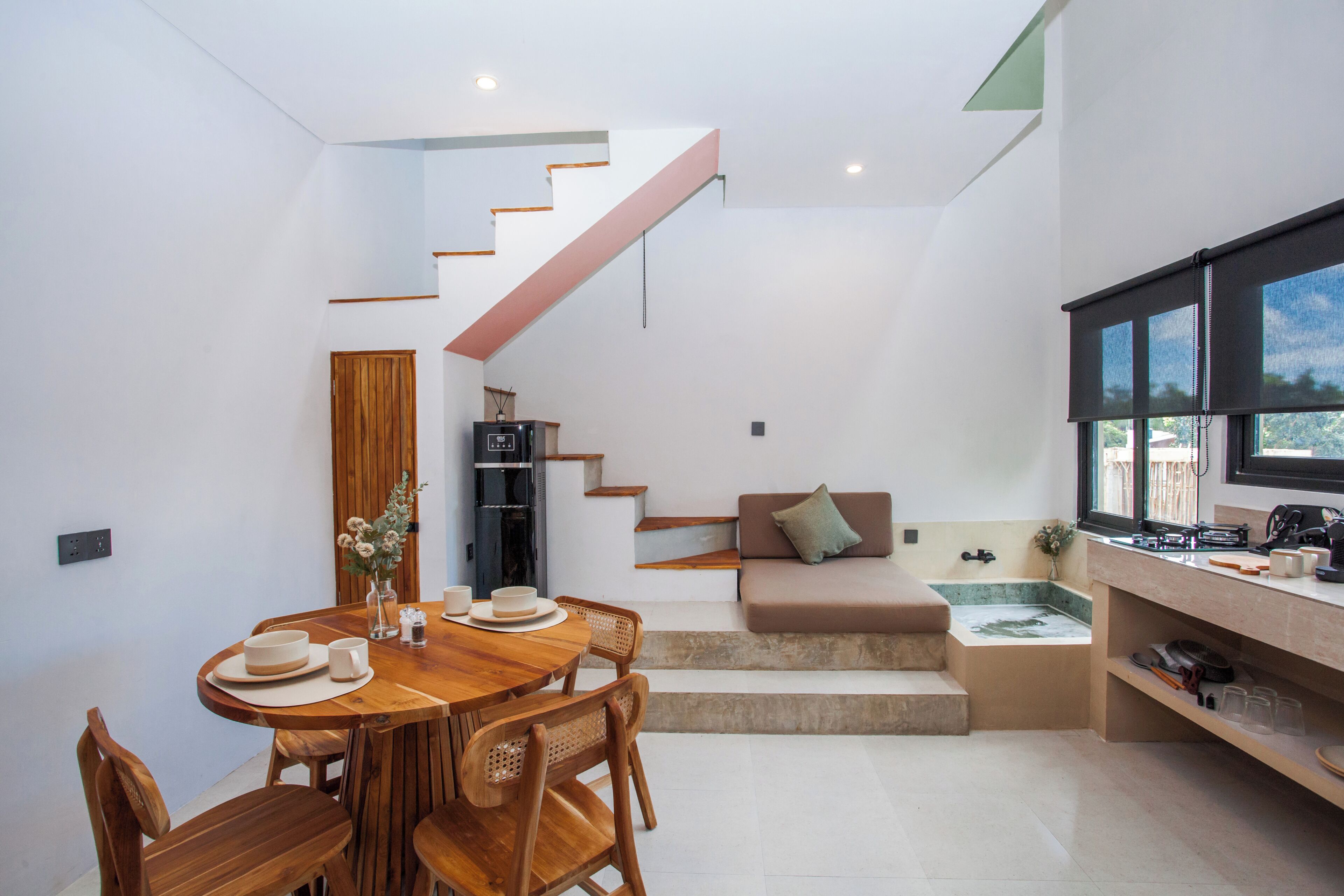 A modern kitchen with a dining area, a staircase, and a seating area with a view.
