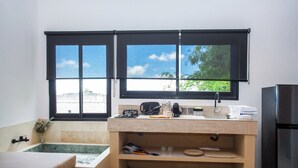 Una cocina compacta con ventana, un lavabo, una encimera y un refrigerador.