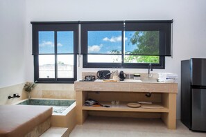 A compact kitchen with a window, a sink, a countertop, and a refrigerator. - Modern 1 bedroom loft - Shanti Loft 6 (Kabupaten Badung)