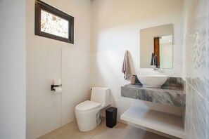 Ein modernes Badezimmer mit Toilette, Waschbecken und Spiegel.