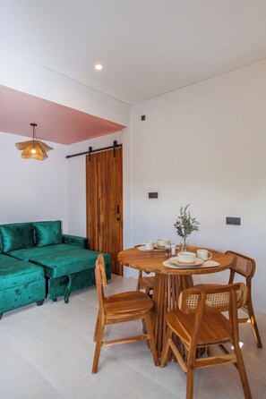 A room with a green sofa, wooden dining table, and chairs. - Modern 1 bedroom loft - Shanti Loft 6 (Kabupaten Badung)