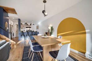 A modern kitchen with white cabinets, a dining area with a wooden table and white chairs, and a staircase leading to another level. - 2 Bedroom 2 Bath just minutes from Keystone! (Dillon)