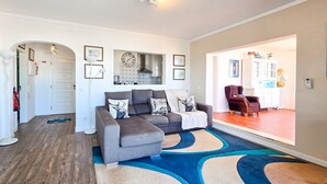 A living room with a sectional sofa, a patterned rug, and a kitchen visible through an archway. - Penthouse Ponta da Areia | Sea & Garage (Portimão)