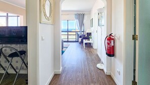 A hallway with wooden flooring, a fire extinguisher, and a view to the outside. - Penthouse Ponta da Areia | Sea & Garage (Portimão)