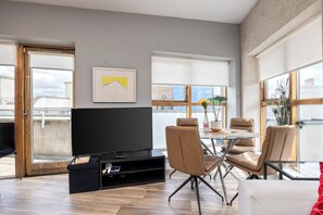 A modern living room with a flat-screen TV, leather chairs, a glass table, and large windows. - Stylish 2BR | Walk to Temple Bar & Dublin Castle (Temple Bar)