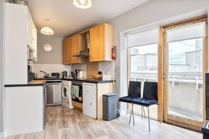 A compact kitchen with modern appliances, wooden cabinets, and a view through a sliding glass door. - Stylish 2BR | Walk to Temple Bar & Dublin Castle (Temple Bar)