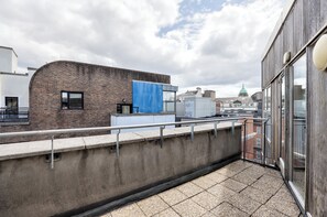 A rooftop terrace with a concrete barrier, a blue tarp, and a view of buildings in the background. - Stylish 2BR | Walk to Temple Bar & Dublin Castle (Temple Bar)