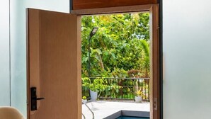 Una camera da letto con un letto, una porta che dà su un balcone con piscina e una sedia.