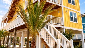Un immeuble jaune à plusieurs étages, doté de balustrades blanches et d’un escalier menant aux niveaux supérieurs.