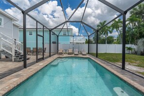 A swimming pool with a covered area, a staircase, and a view of houses in the background. - Palermo Paradise (Fort Myers Beach)
