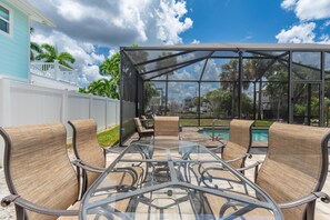 A glass-enclosed patio with wicker furniture and a view of a swimming pool. - Palermo Paradise (Fort Myers Beach)