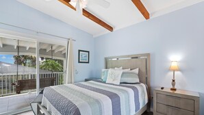 Une chambre à coucher comprenant un lit, une table de chevet, une lampe, une fenêtre donnant sur un beau paysage et un balcon.