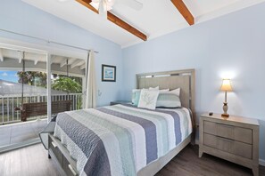 A bedroom with a bed, a nightstand, a lamp, a window with a view, and a balcony. - Palermo Paradise (Fort Myers Beach)