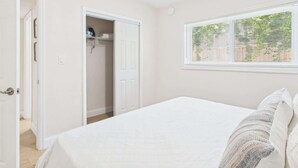 Une chambre à coucher avec un lit, une fenêtre avec des stores, un placard et une porte.
