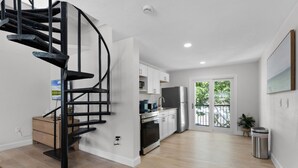 Eine moderne Küche mit Wendeltreppe, weißen Schränken und Blick ins Freie.