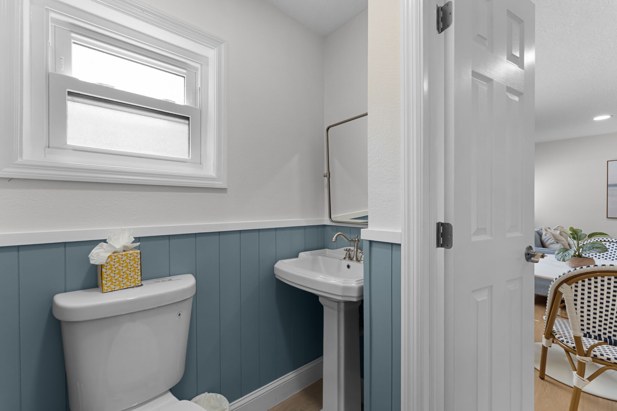A bathroom with a toilet, sink, and window.